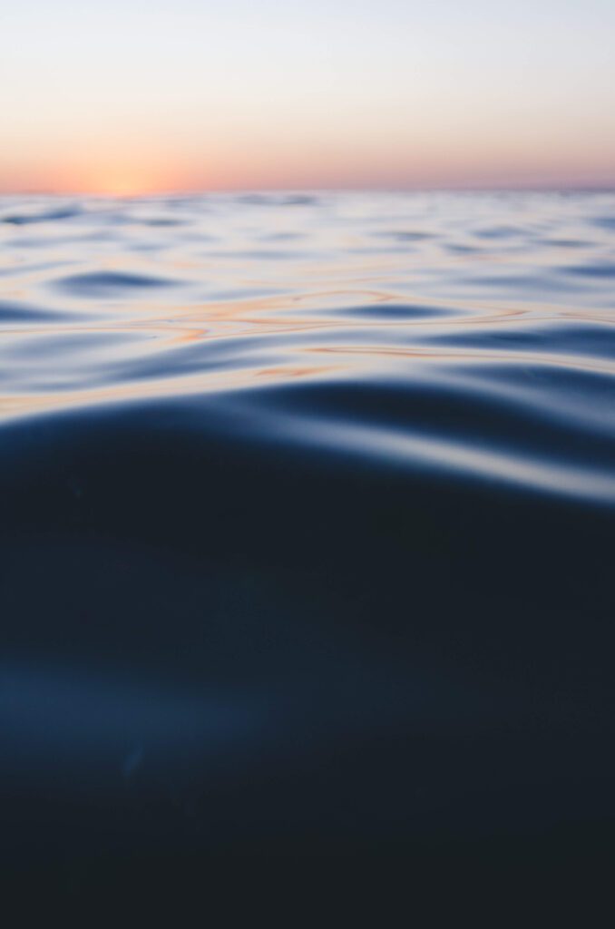 Surfer point of view of sun setting behind ocean horizon in Jaco, Puntarenas Province, Costa Rica